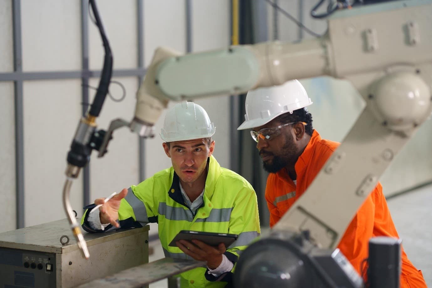 Two people dressed in illumious construction clothing looking at technological machinery