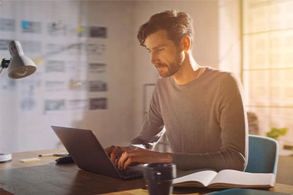 Freelancer sat at his desk working on his laptop