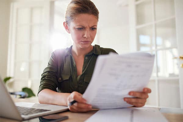 A Contractor’s Guide to IR35 - Part 5 - Female contractor sat at desk look confused as she reads IR35 paper documents.