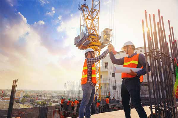 Two trades professionals on a construction site raising their hands together in celebration of their success.