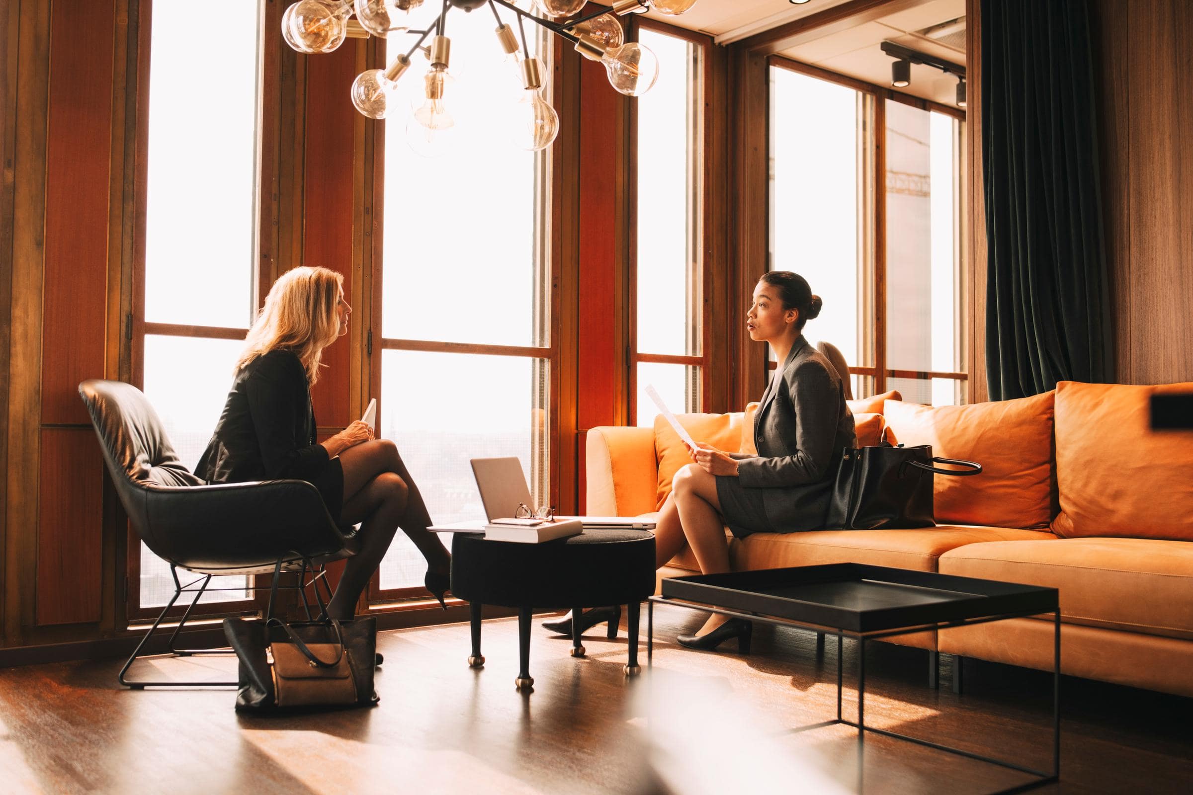 Two ladies sat opposite each other, discussing paperwork they are holding