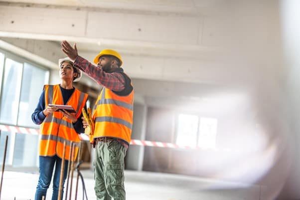 Two construction workers in high vis stood in a bulding in construction