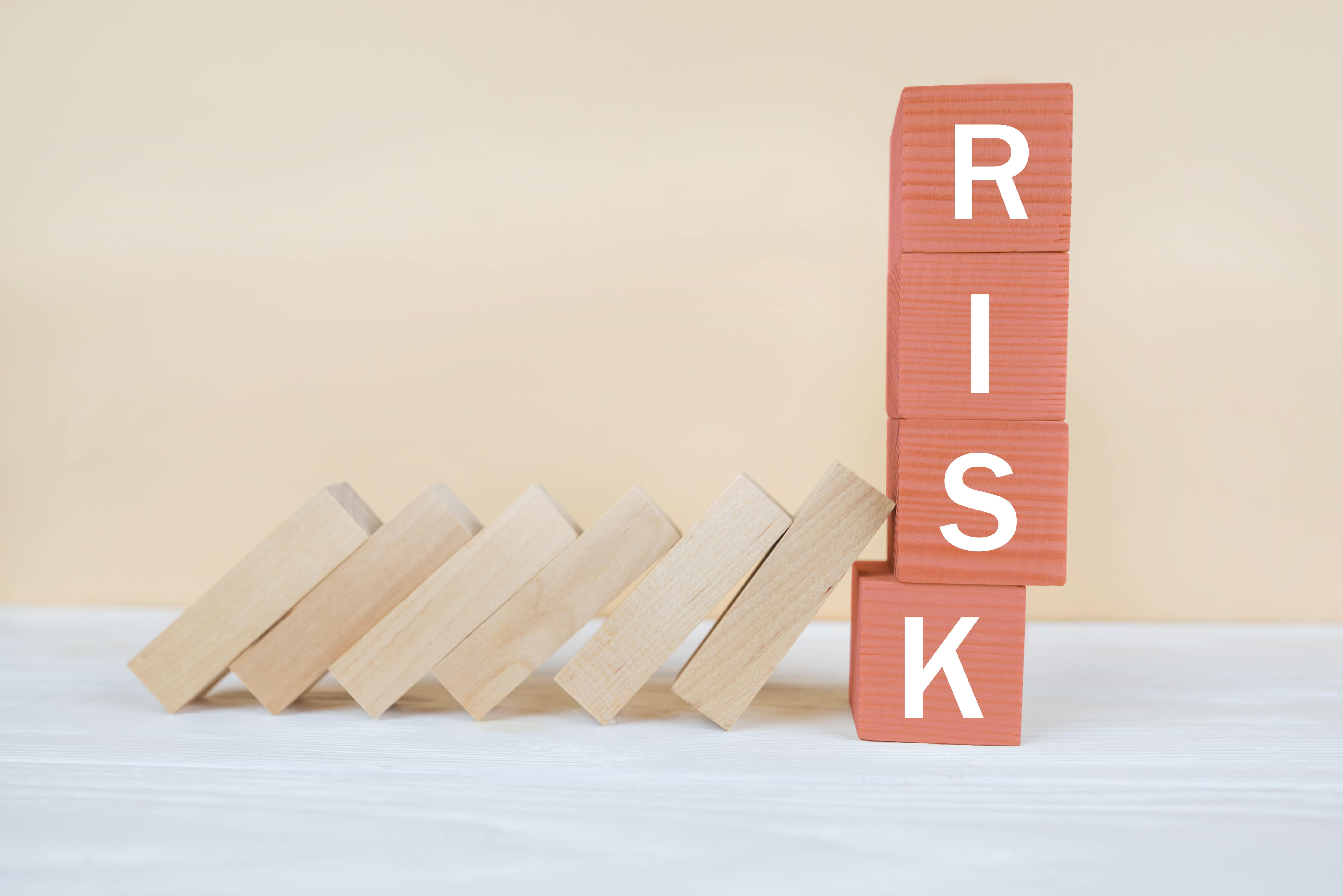 Red RISK cube blocks stop falling blocks on table.