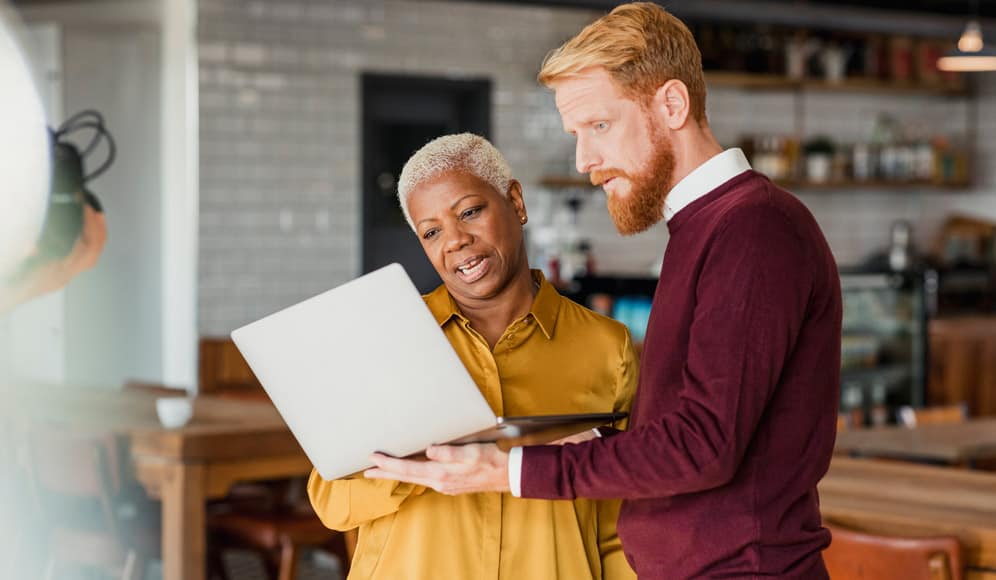 Two colleagues having a discussion whilst looking at a laptop