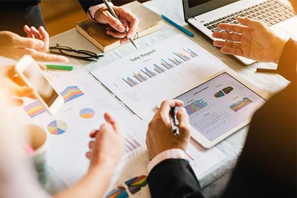 A small business team sat around a table discussing cash flow and analysing sales reports.