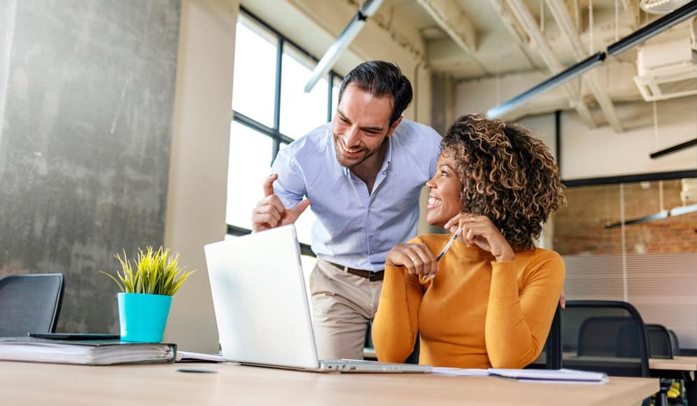 Two people smiling at a computer