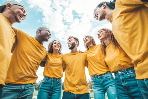A group of volunteers wearing matching yellow tshirts, hugging and laughing