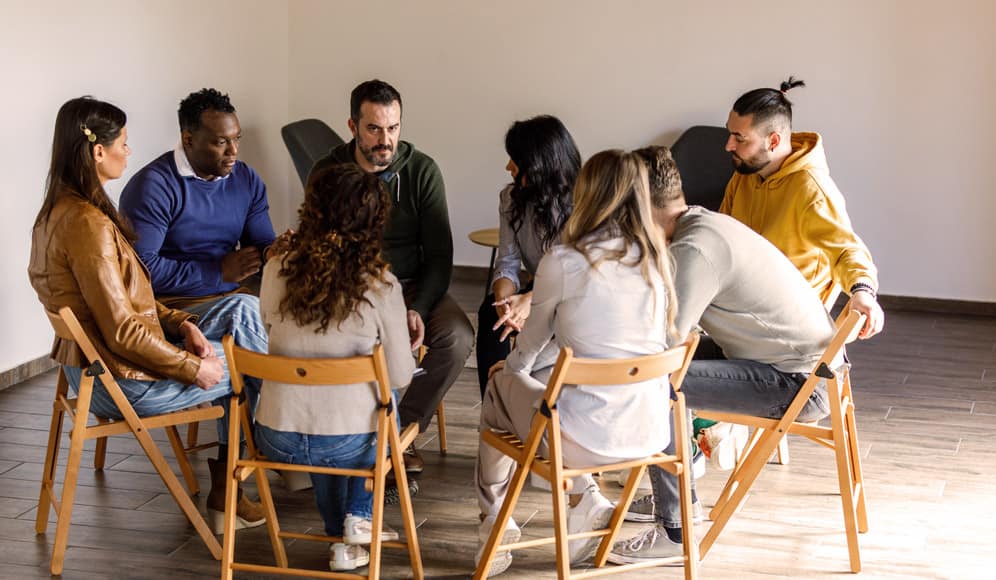 A group of people sat on fold out chairs in a circle