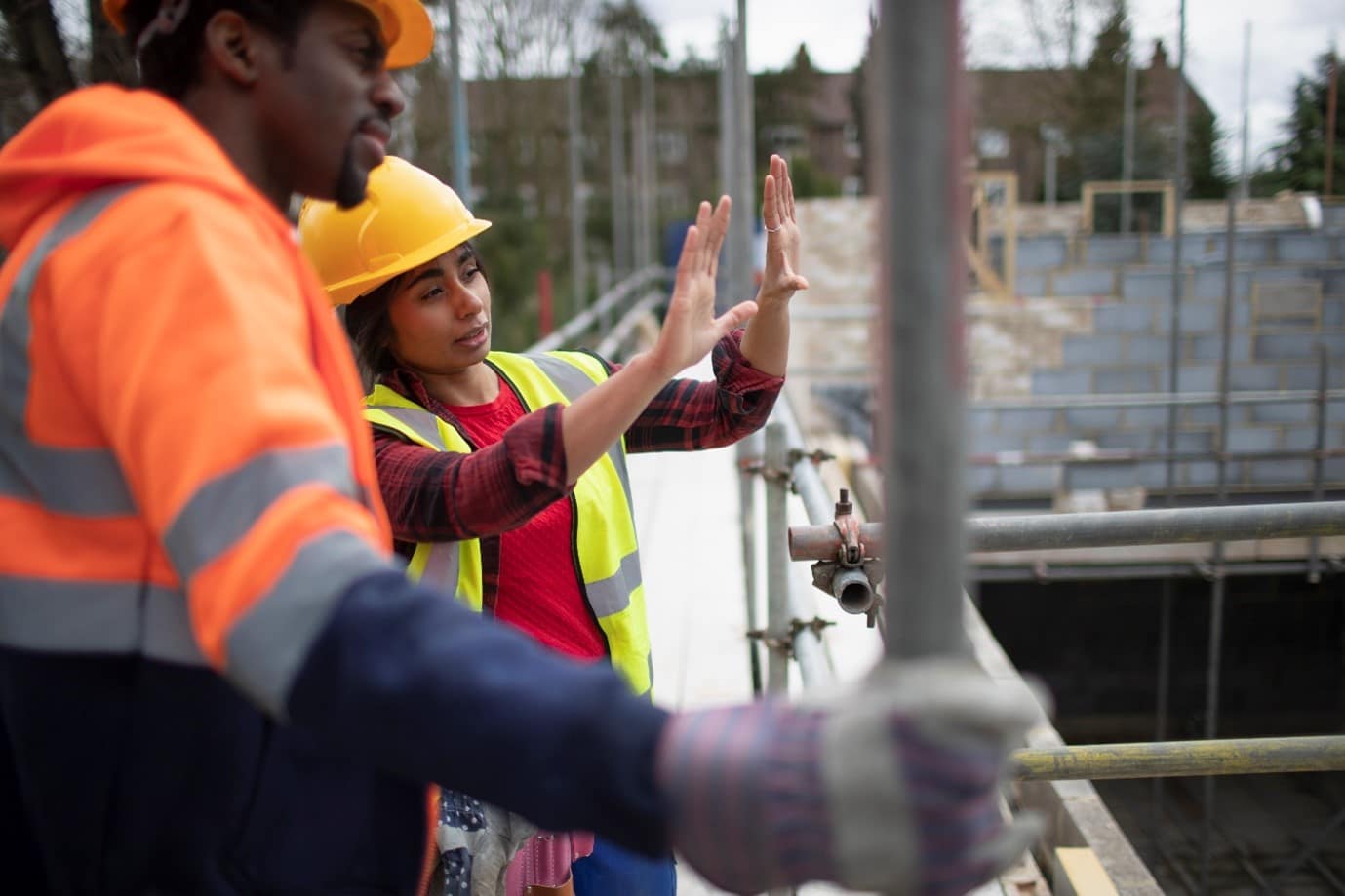 Two construction workers discussion having a discussion next to scaffolding