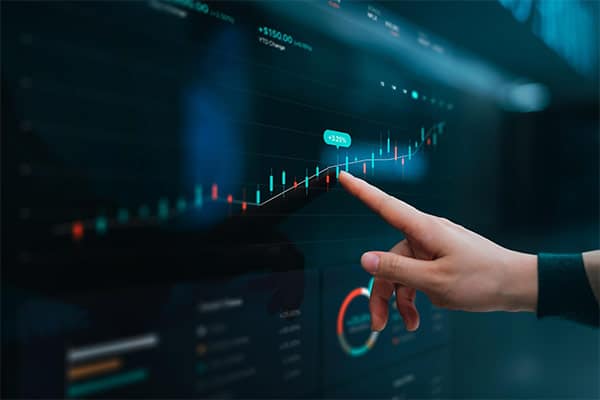 A business owner's hand pointing at a chart on their computer.