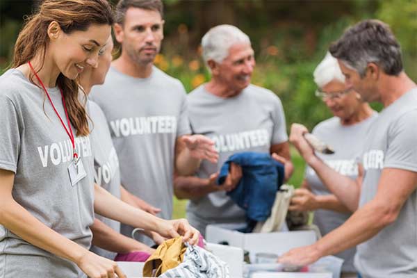 A group of charity volunteers standing together around a table of donated items
