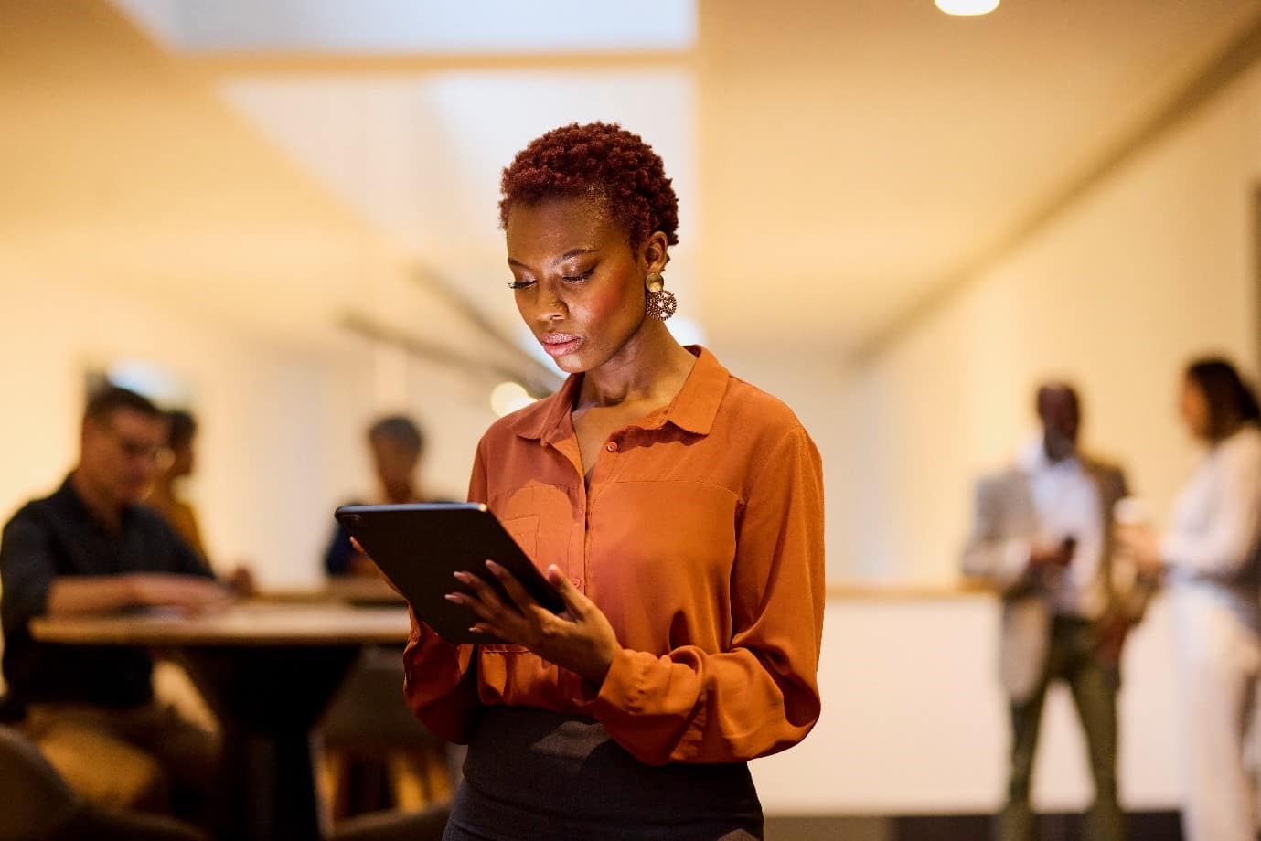 someone looking at their tablet with a serious face, in front of a group of people