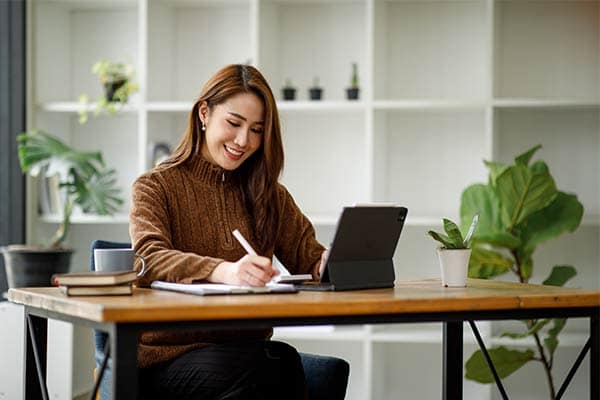 A freelancer sat at her desk working from her iPad.