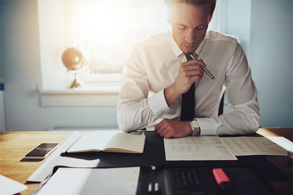 A Contractor’s Guide to IR35 - Part 5 - Female contractor sat at desk look confused as she reads IR35 paper documents.