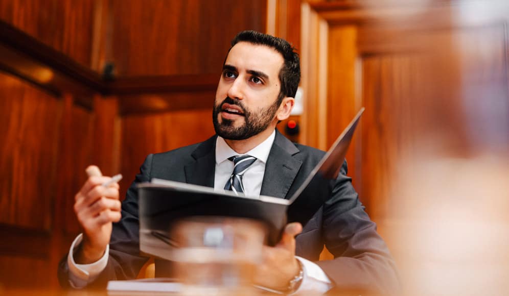 A man in a suit holding a binder