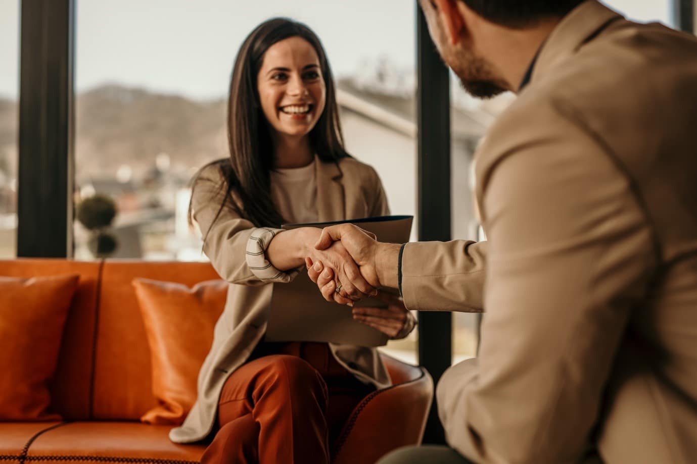 Two people shaking hands, we can see one face which is smiling