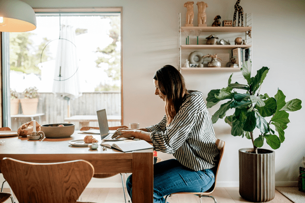 A freelancer working on their laptop sat at their kitchen table
