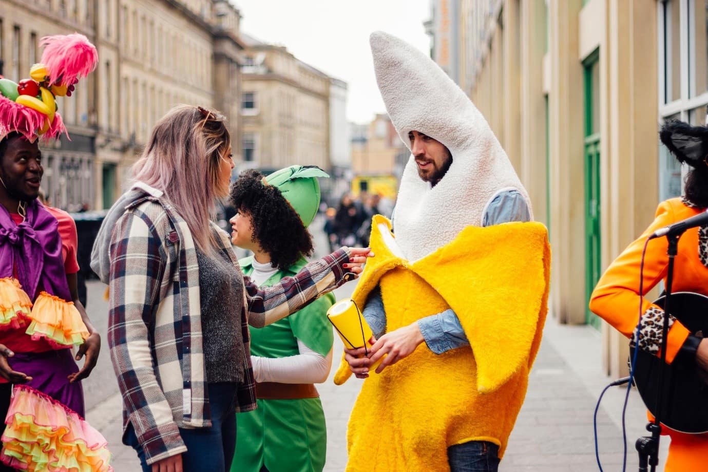 People dressed in: a carnival outfit, peterpan costume, a banana costume, holding money boxes for fundraising