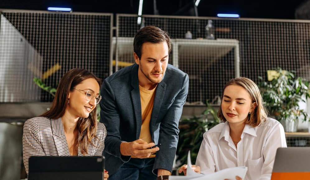 Three office workers discussing paperwork