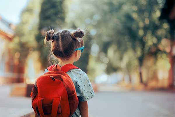 Girl wearing a red backpack and sunglasses looking into the distance 