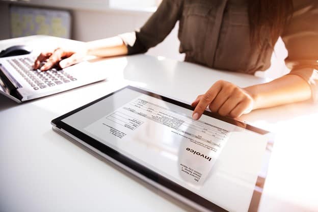 A businesswomen checking a digital invoice on a tablet.
