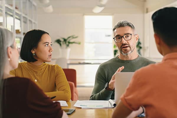 A freelancer sat around a table with his client addressing an unpaid invoice.