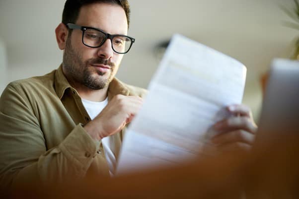 A man with glasses on looking at a form on a white piece of paper