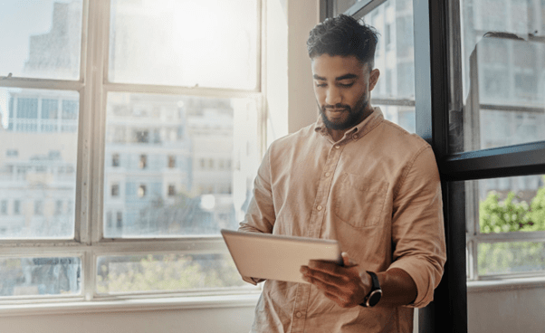 A businessman looking at a tablet by a window