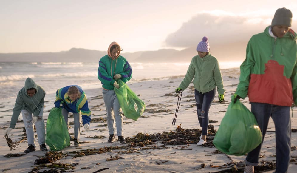 A group of 5 volunteers cleaning up rubbish on a beach