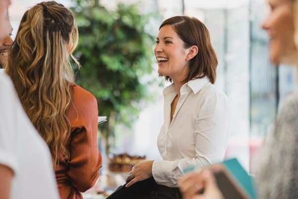 Two people in professional clothing talking to each other at what appears to be a networking event