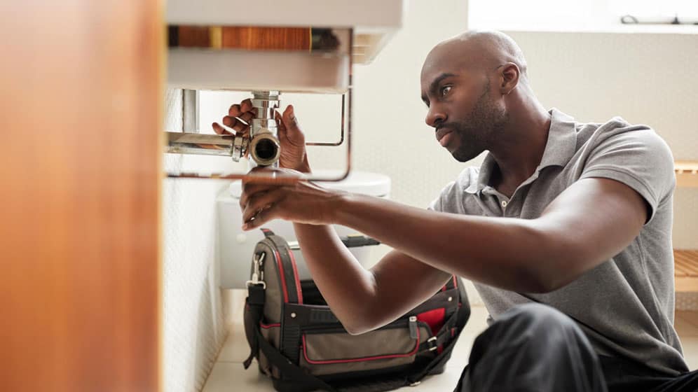Plumber fixing underneath a sink