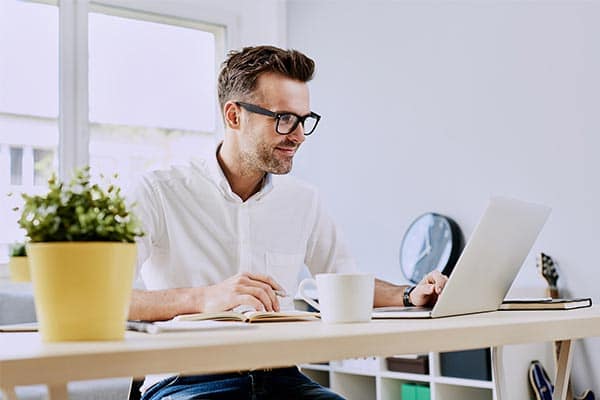 A self-employed contractor sat at his desk working from his laptop.