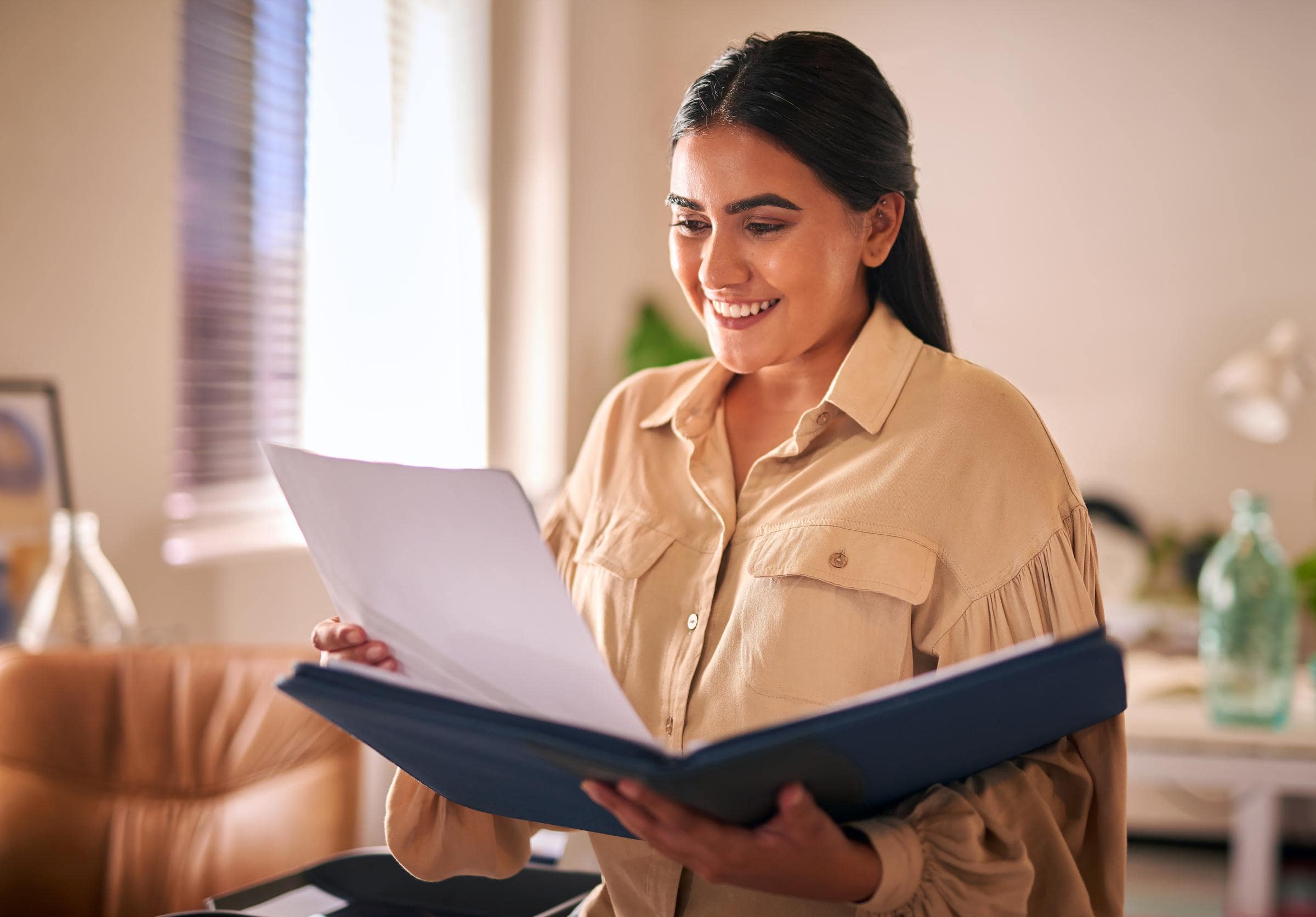 A woman smiling, looking down at a report