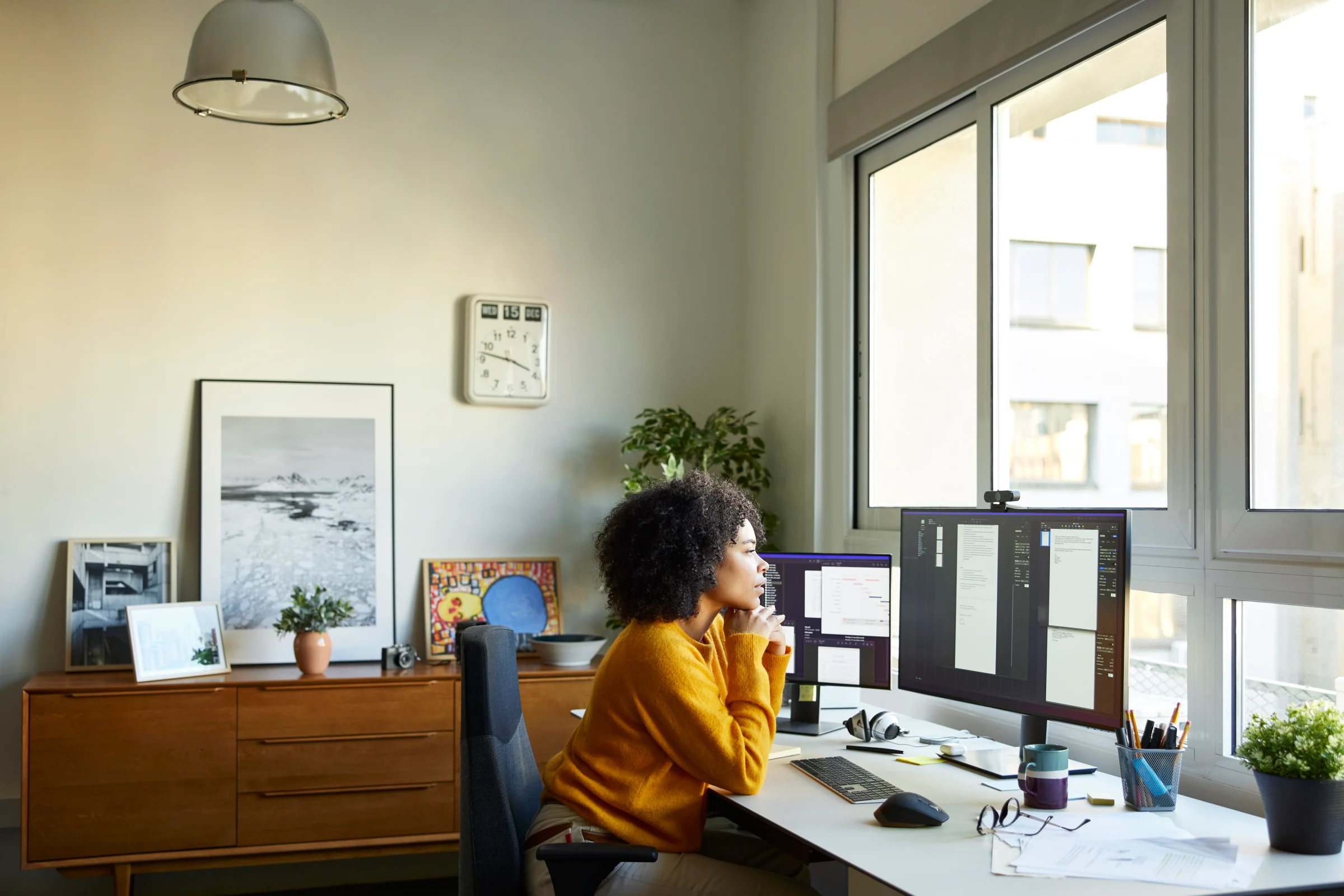 Someone sat in a home office looking at 2 computer screens
