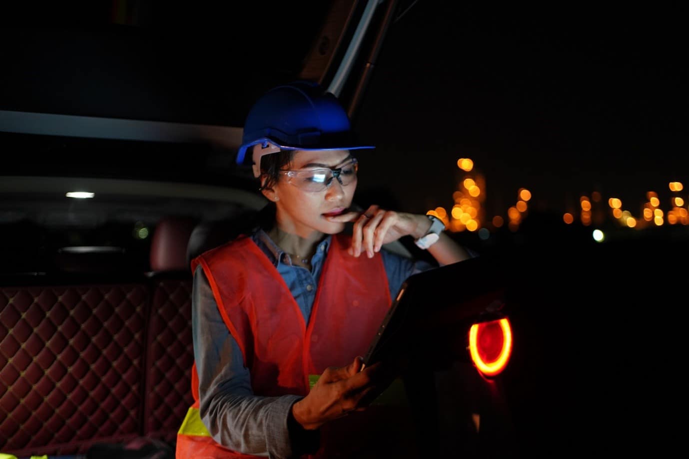A construction worker checking over an electronic tablet whilst on a dark site