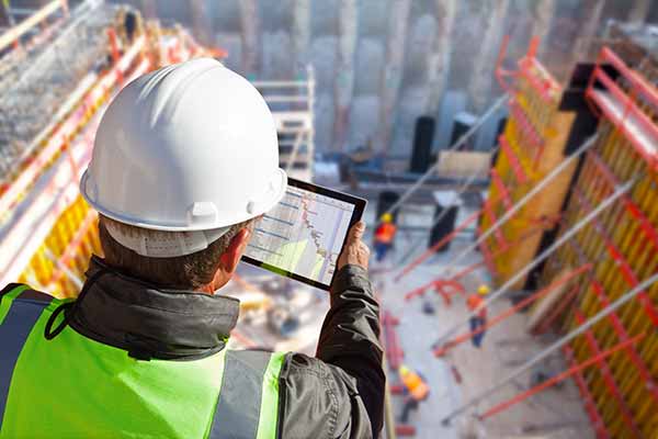 A self-employed builder on a building site looking at an iPad.