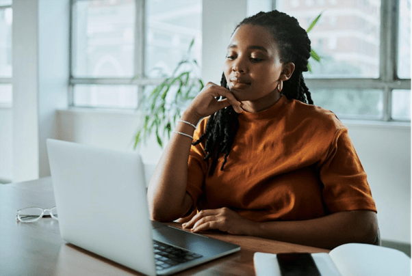 Someone sat at a table in an office, looking at a laptop
