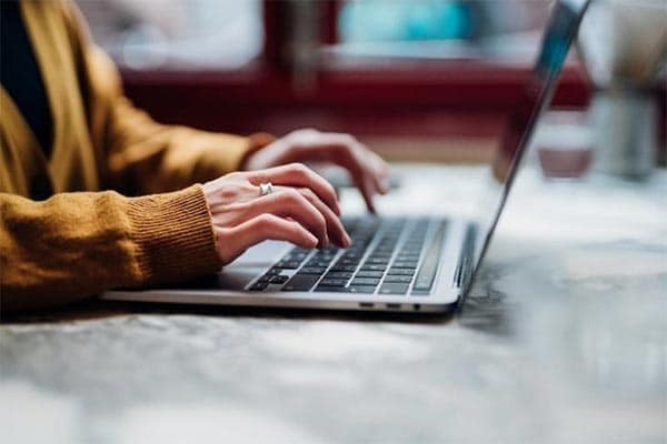 A close up shot of hands typing on a laptop keyboard.