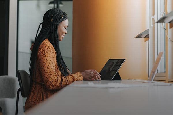 Small business owner sat at her desk working from an iPad.