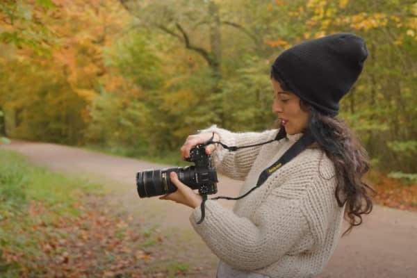 A side view of a lady in a park, taking pictures on her large camera