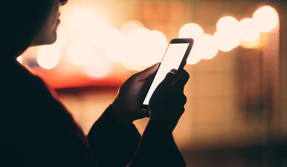 Someone holding a lit up mobile phone