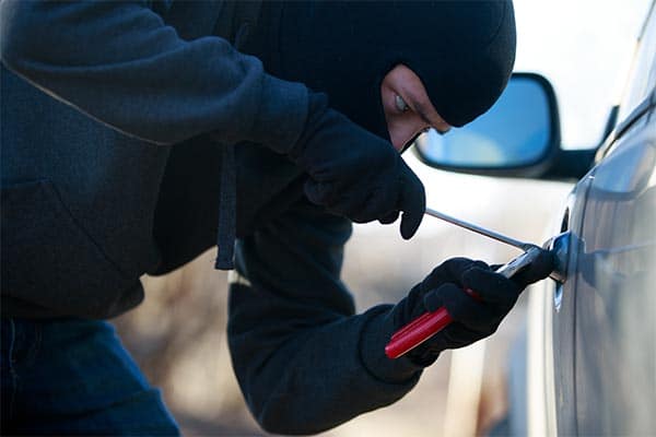 A thief trying to break into a tradesperson's work van.
