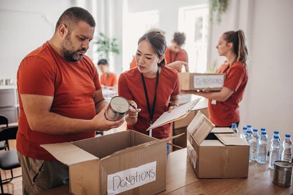 A group of volunteers unpacking tinned food from cardboard donation boxes