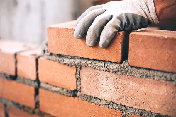 A bricklayer’s trowel laying next to a completed wall