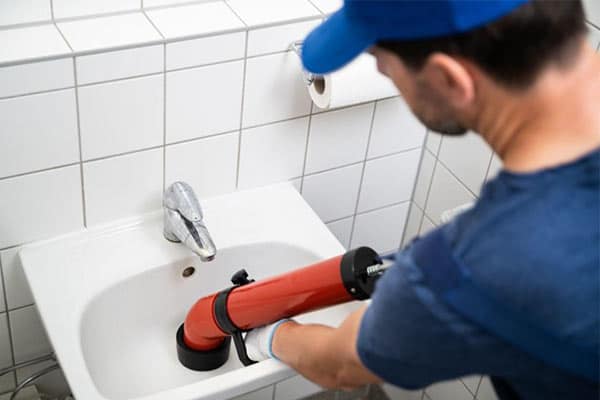 A drain cleaner using a plunger to remove a blockage from a sink.