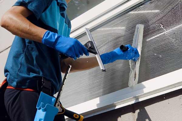 a man dressed in cleaning uniform cleaning a window
