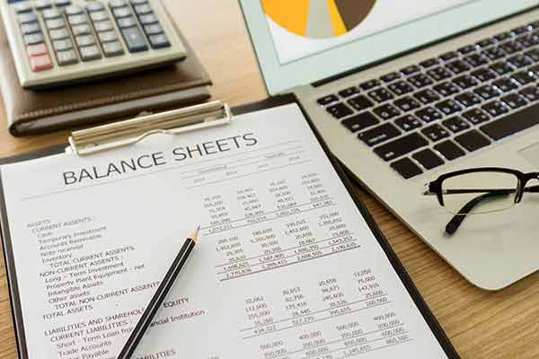 Understanding the balance sheet - an image of a balance sheet on a clipboard next to a calculator and laptop