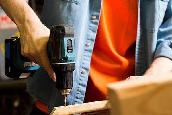 A joiner drilling through a piece of wood.