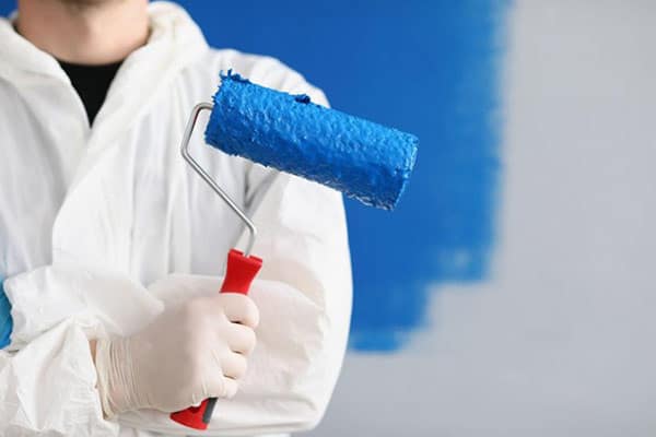 A close-up of a painter/decorator holding a roller tool for painting walls.