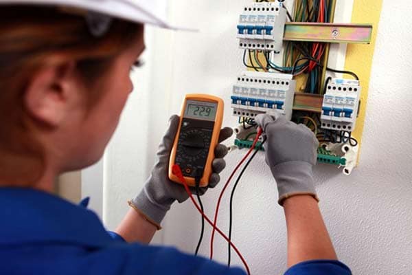 An electrician using a multimeter to check the current running through a wire